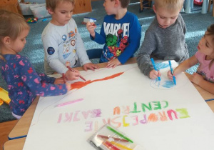 Grupa dzieci wykonuje plakat – kolorują wodę, drogę.